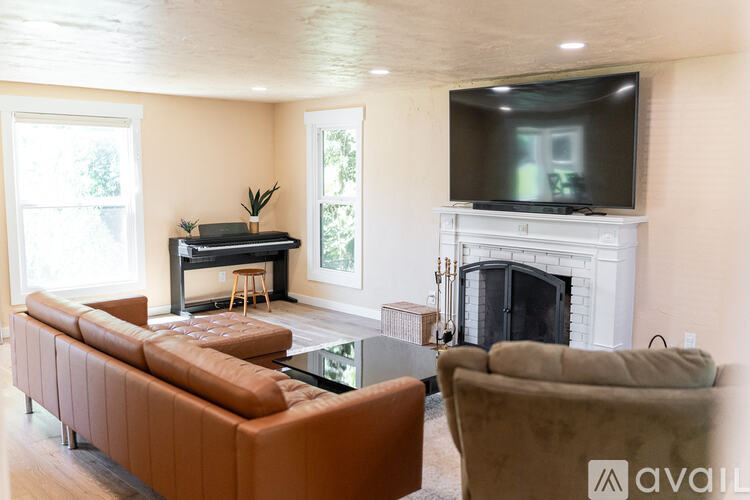 A living room with a brown sofa, a glass table, a television, and a fireplace.