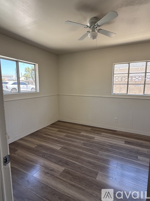 A room with a ceiling fan and wood flooring.