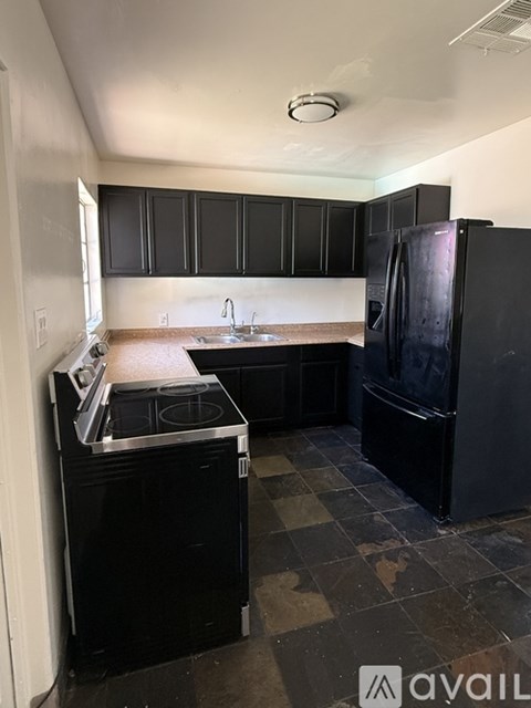 A kitchen with black cabinets and a black fridge.