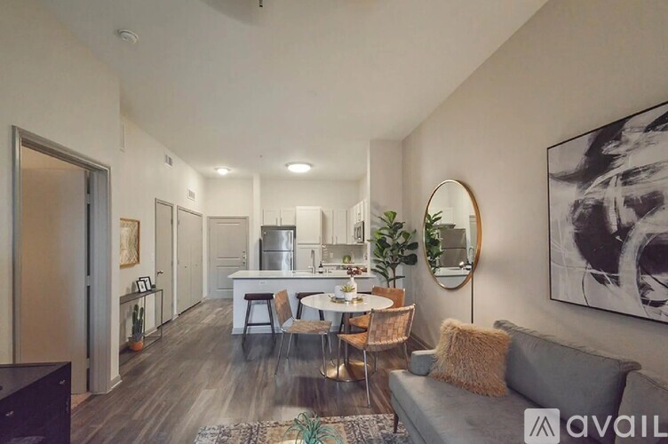 A living room with a grey couch, a round mirror, and a painting on the wall.