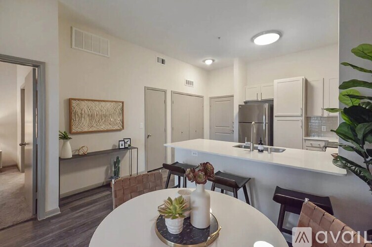 A kitchen with white countertops and a dining table set with a plant on it.