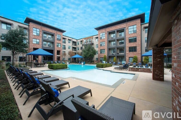 A swimming pool surrounded by lounge chairs and umbrellas in front of apartment buildings.