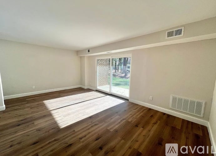 A room with wooden floors and a window showing a view of trees outside.