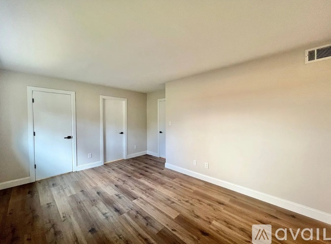 A room with wooden flooring and three doors.