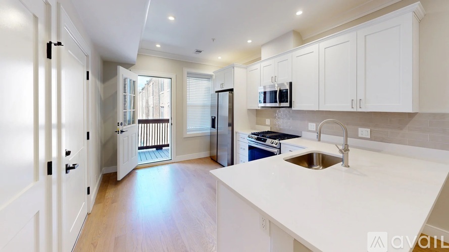 A kitchen with white cabinets and a wooden floor.