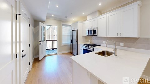 A kitchen with white cabinets and a wooden floor.