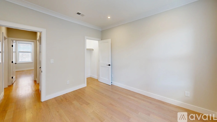 A room with wooden floors and white walls, with a door on the right side.