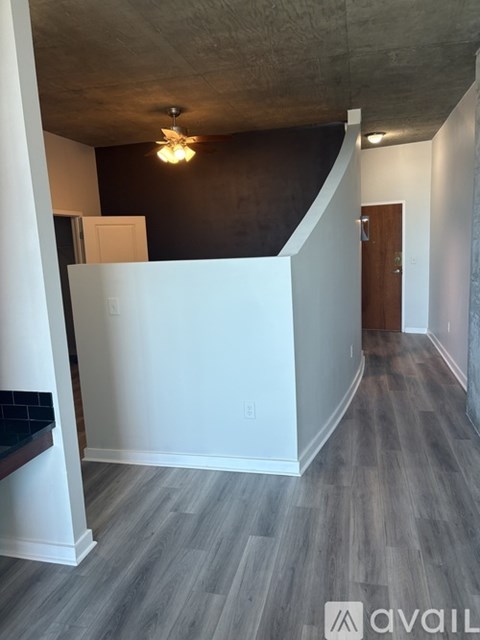 A small, empty walk-in closet with a wooden floor and white walls.