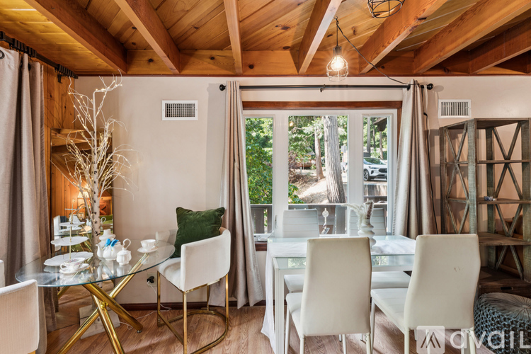A dining room with a glass table and white chairs.