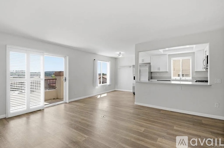 A spacious living room with wooden floors and white walls.