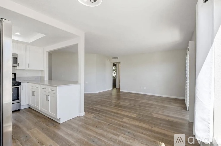 A spacious kitchen with white cabinets and a wooden floor.