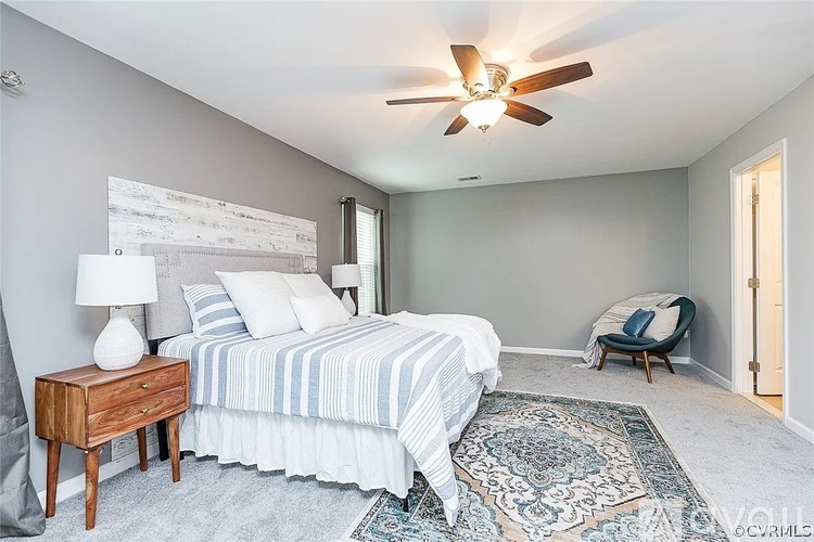 A bedroom with a bed, nightstand, and chair.