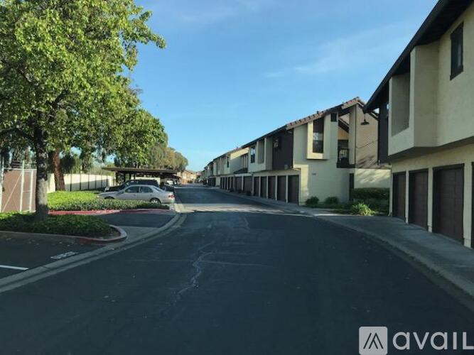 A street view of a residential area with houses on both sides and a car parked on the side of the road.