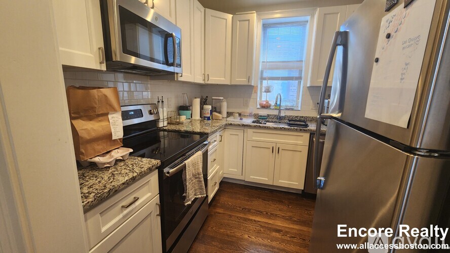 A kitchen with white cabinets and a black countertop.
