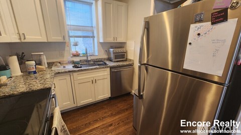 A kitchen with a stainless steel refrigerator and wooden floors.