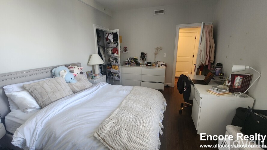 A bedroom with a large bed and a desk with a lamp.