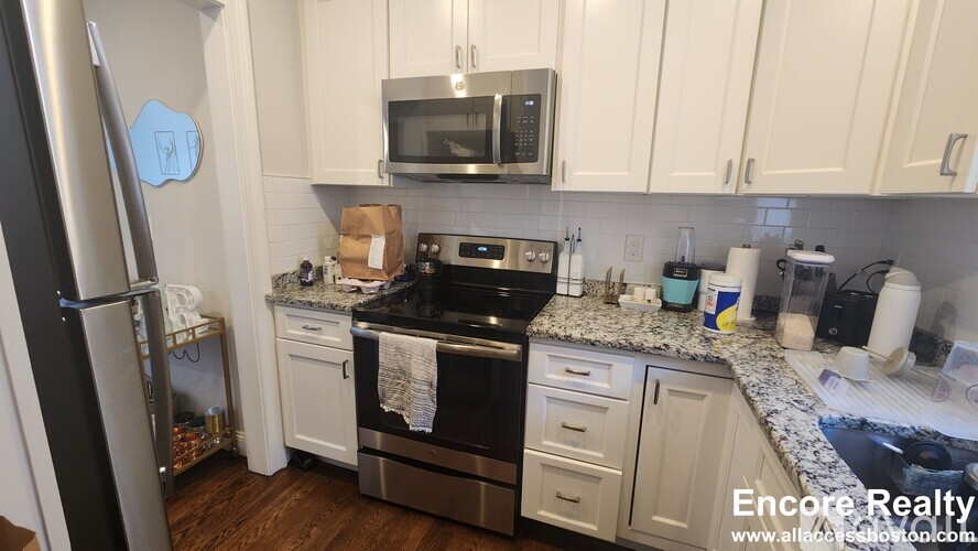 A kitchen with white cabinets and a black stove top.