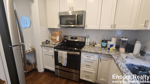 A kitchen with white cabinets and a black stove top.