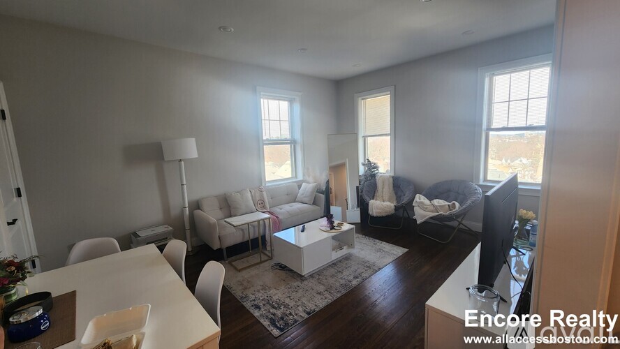 A living room with a white couch, a white coffee table, and a white chair.