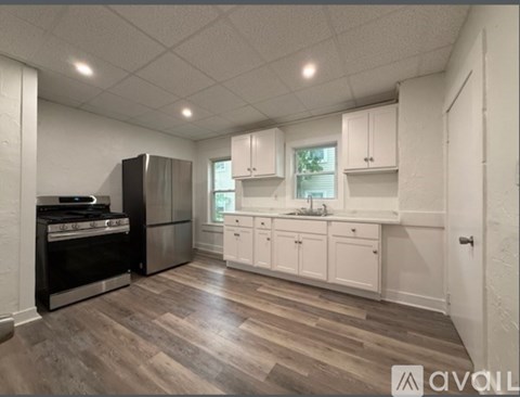 A kitchen with white cabinets and a wooden floor.