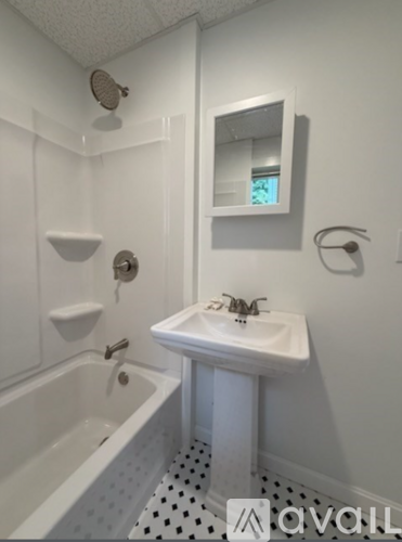 A white bathroom with a sink, mirror, and bathtub.