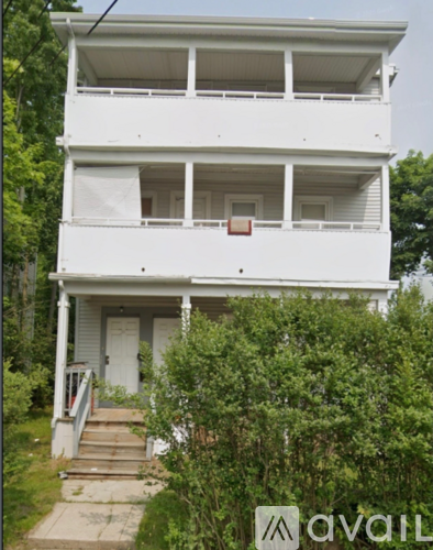 A white two-story house with a balcony on the second floor.
