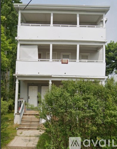 A white two-story house with a balcony on the second floor.