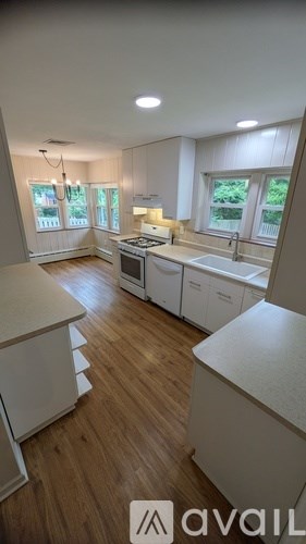 A kitchen with white cabinets and a wooden floor.