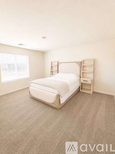 A bedroom with a bed, nightstand, and window.