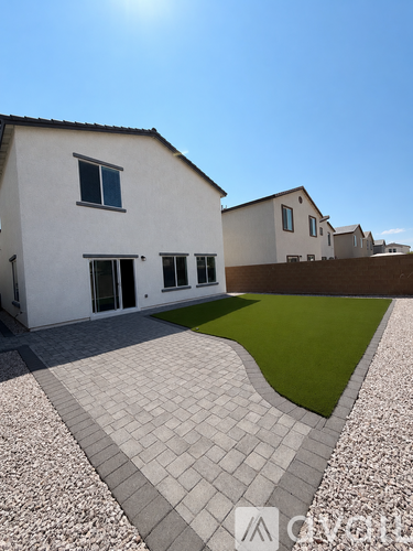 A white house with a grey tiled walkway in front.