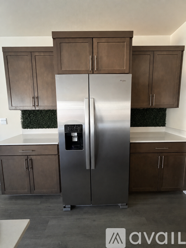 A stainless steel refrigerator in a kitchen with brown cabinets.