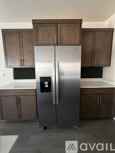 A stainless steel refrigerator in a kitchen with brown cabinets.