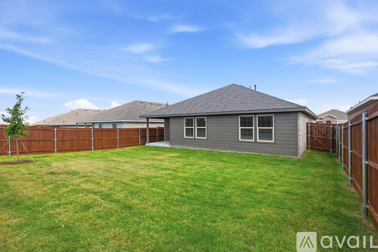 A house with a grey roof and a brown fence is available for rent.