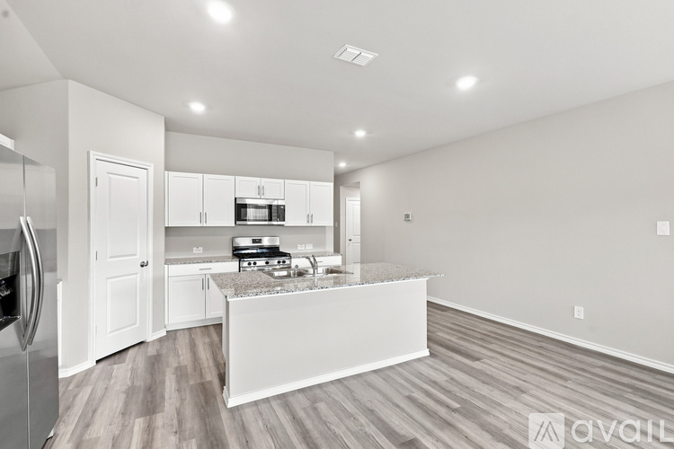 A kitchen with white cabinets and a marble island.