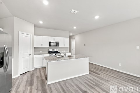 A kitchen with white cabinets and a marble island.