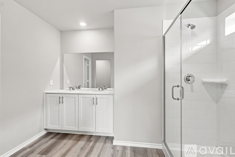 A white bathroom with a walk-in shower and a vanity with a mirror.