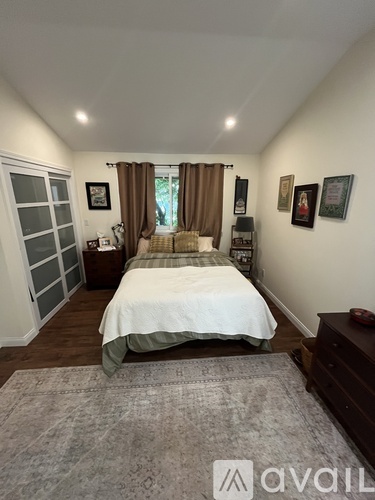 A bedroom with a bed, nightstand, and pictures on the wall.