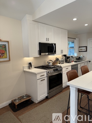 A kitchen with white cabinets and a black microwave above the stove.