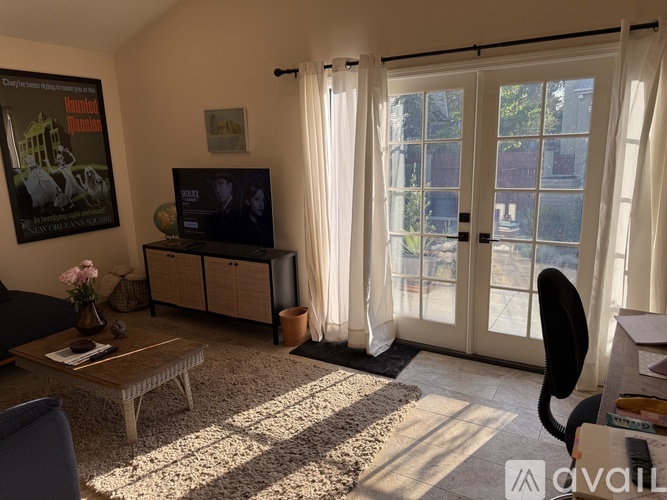 A living room with a flat screen TV and a glass door leading outside.