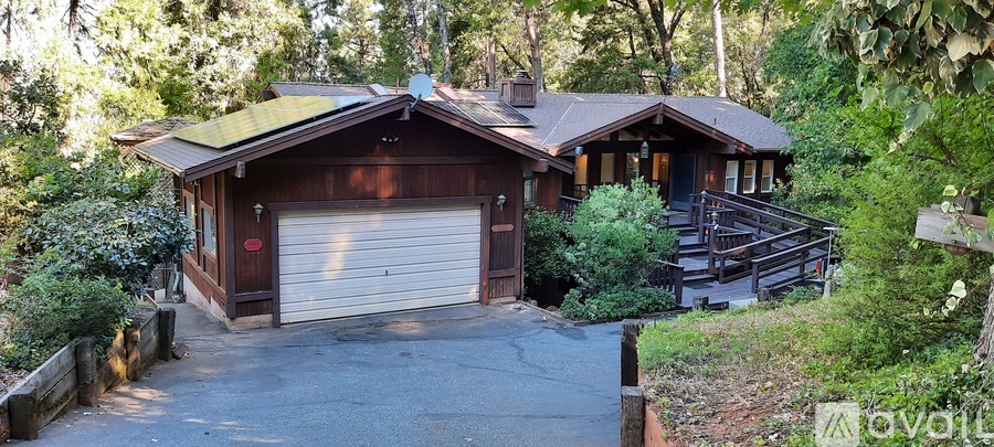 A house with a garage is surrounded by trees.