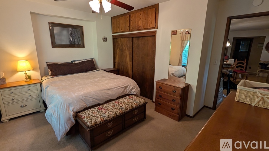 A bedroom with a bed, nightstand, and a dresser with a mirror.