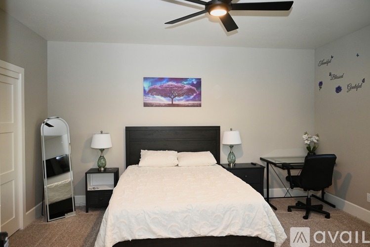 A bedroom with a large bed, a desk with a chair, and a ceiling fan.