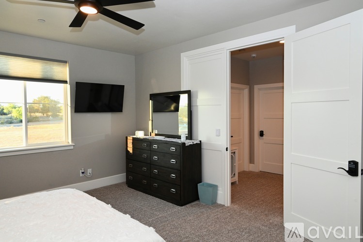 A bedroom with a bed, dresser, and two TVs.