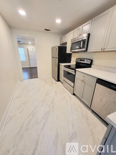 A kitchen with white cabinets and a marble floor.