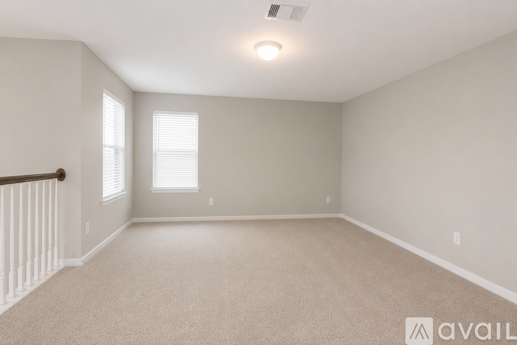 A spacious room with beige carpeting and a window with blinds.