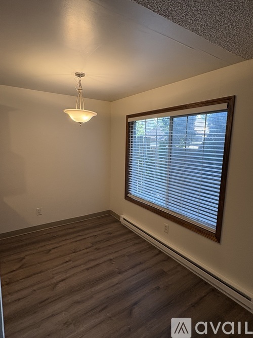 A room with wooden floors and a window with blinds.