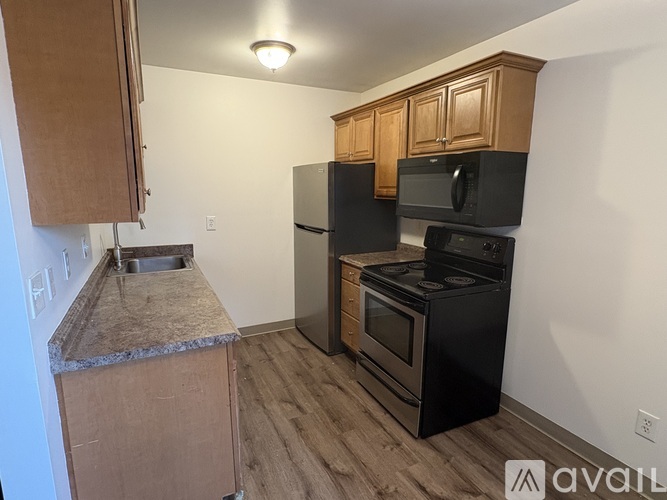 A kitchen with black appliances and wooden cabinets.