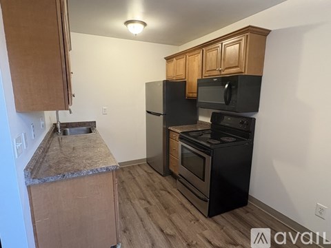 A kitchen with black appliances and wooden cabinets.