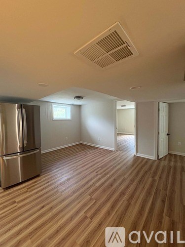 A kitchen with a stainless steel refrigerator and wooden flooring.