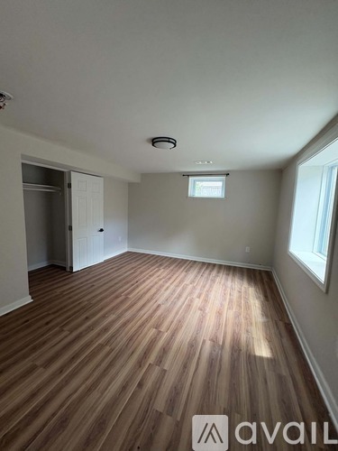 A room with wooden flooring and a window on the right side.